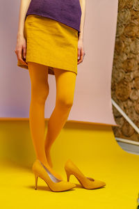 Low section of woman standing in yellow shoes