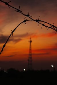 Silhouette of barbed wire against sky during sunset