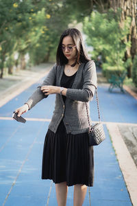 Portrait of young woman standing against trees