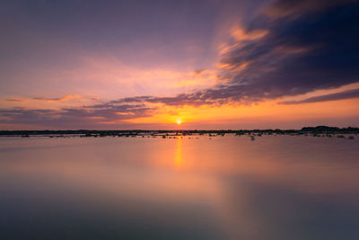 Scenic view of sea against dramatic sky during sunset