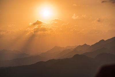 Scenic view of silhouette mountains against orange sky