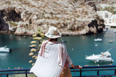 Rear view of woman looking at sea while standing by railing