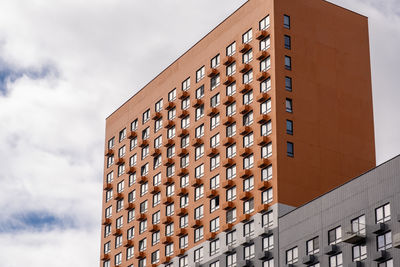 Low angle view of modern building against cloudy sky