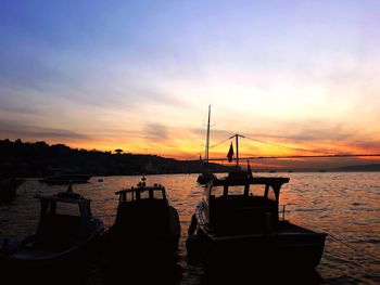 Silhouette sailboats moored on sea against sky during sunset