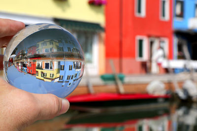 Close-up of hand holding crystal against building