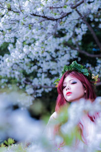 Low angle view of woman below flowers on tree