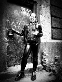 Full length portrait of teenage girl standing against wall