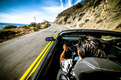 Rear view of man riding motorcycle on road