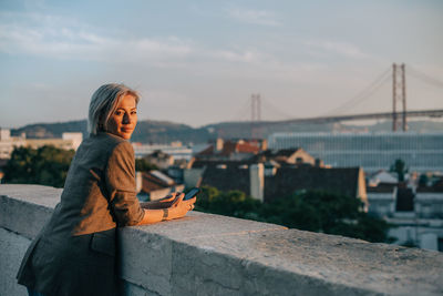 Woman using mobile phone against sky