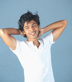 Portrait of young man standing against blue background