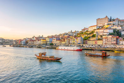 Porto in portugal in warm winter sunset light with boats and douro river in foreground