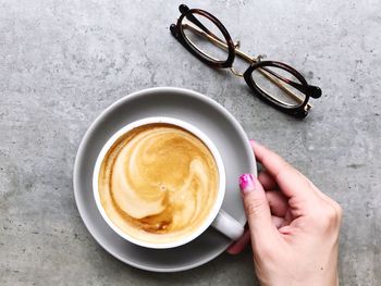 High angle view of woman holding coffee cup on table