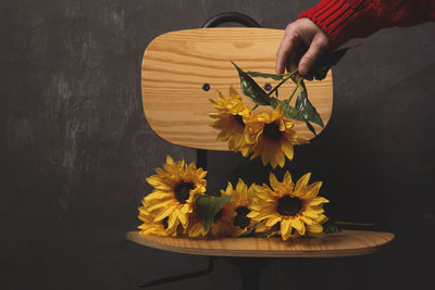 Close-up of hand holding yellow flowers on table