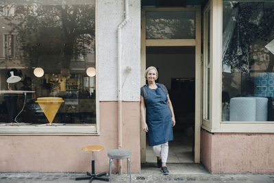 Portrait of smiling woman standing against built structure