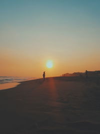 Silhouette person on beach against sky during sunset