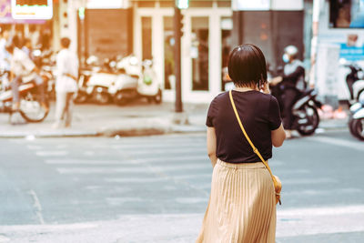 Rear view of woman walking on road in city