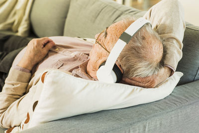 Senior man lying on the couch hearing music with headphones