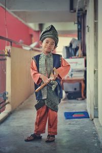 Portrait of boy holding umbrella against built structure