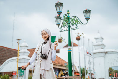 Portrait of young woman standing against building