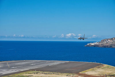 Airplane flying over sea against blue sky