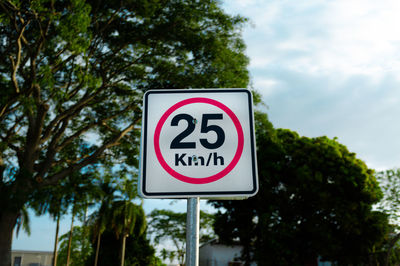 Low angle view of road sign against tree 