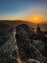 Scenic view of rocks in mountains against sky during sunset