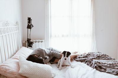 Young woman sleeping by dog on bed at home