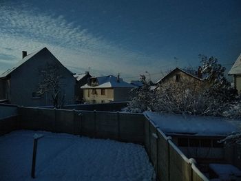 Snow covered houses and trees against sky