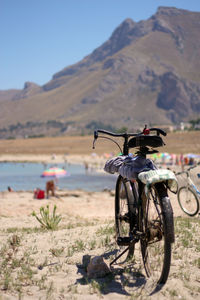 Bicycle on beach against mountains
