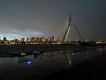 Illuminated bridge over river against sky at night