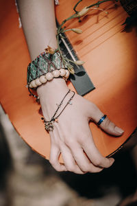 Female hands with boho accessories bracelets made of colored beads holding guitar