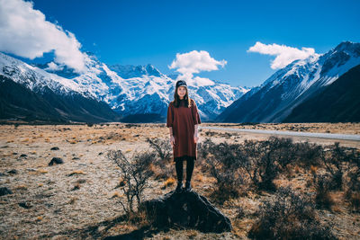 Woman standing on snowcapped mountain against sky