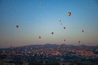 Hot air balloons flying in city against clear sky