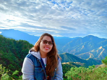 Portrait of young woman against mountains