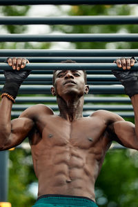 Rear view of shirtless man standing against wall