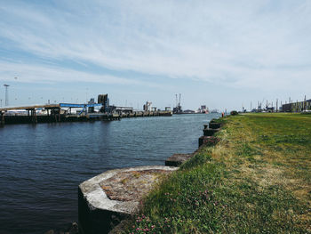 Bridge over river by buildings against sky