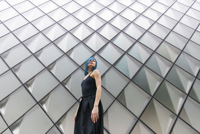 Young woman with dyed hair standing in front of patterned wall