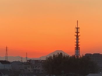 Silhouette tower and buildings against orange sky