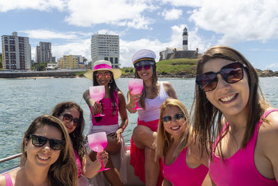 Female friends on top of a boat against the sea in the background. 