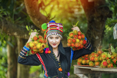 Portrait of smiling woman standing against multi colored flowers