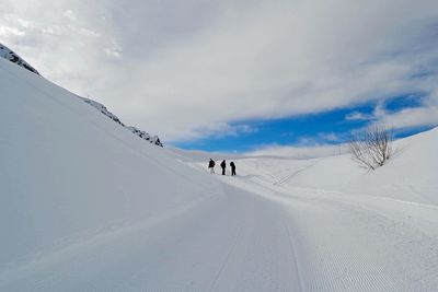 People on snow covered field against sky