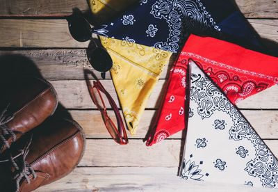 Directly above shot of colorful handkerchiefs by sunglasses and shoes on hardwood floor