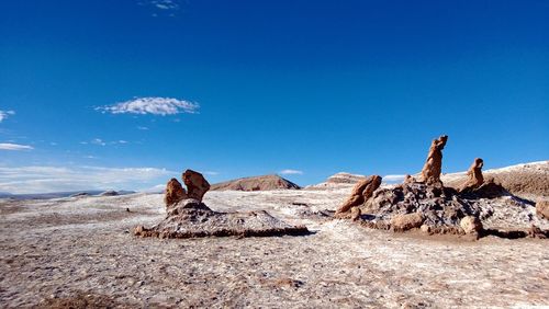 Stack of rocks on landscape against blue sky