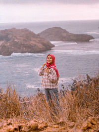 Woman standing by mountain against sky