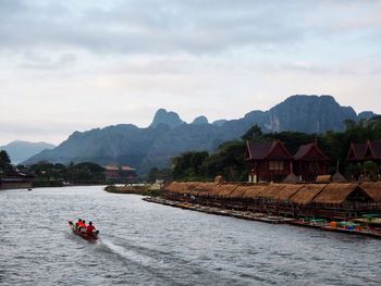 People on boat in river against sky
