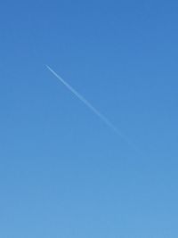 Low angle view of vapor trails against clear blue sky