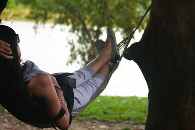 Woman relaxing in hammock at lakeshore