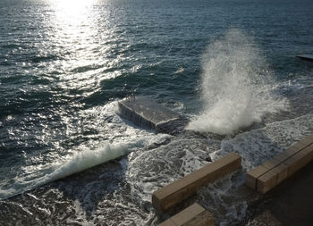 High angle view of waves breaking against sea