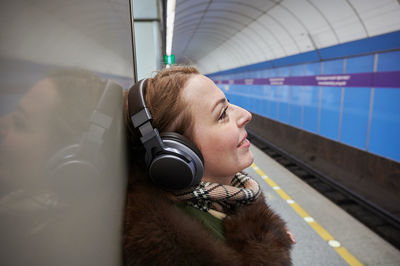 Close-up of smiling woman listening music at subway station