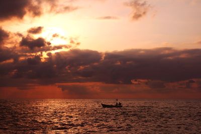 Silhouette sailboat in sea against sky during sunset